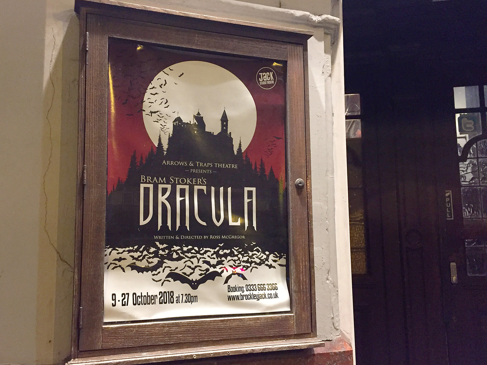 Poster for the production of Dracula, in a wooden frame fixed to a wall.