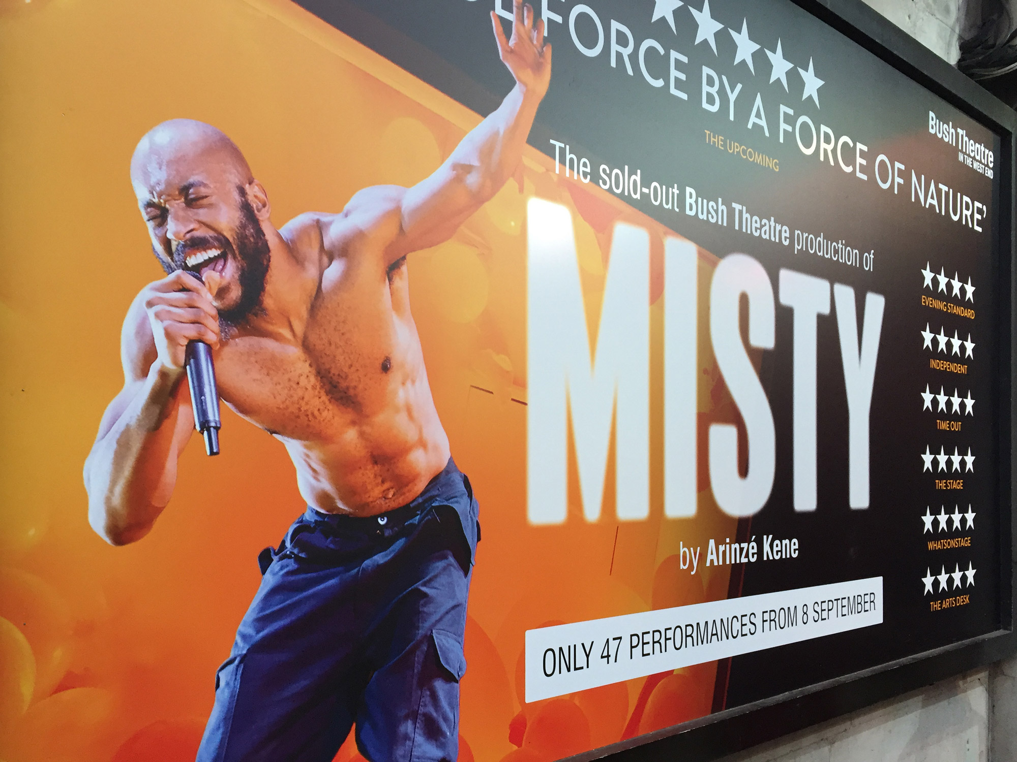 On an orange background, a landscape poster shows a muscly man, with bald head and beard, singing into a microphone. Beside him is the word MISTY...