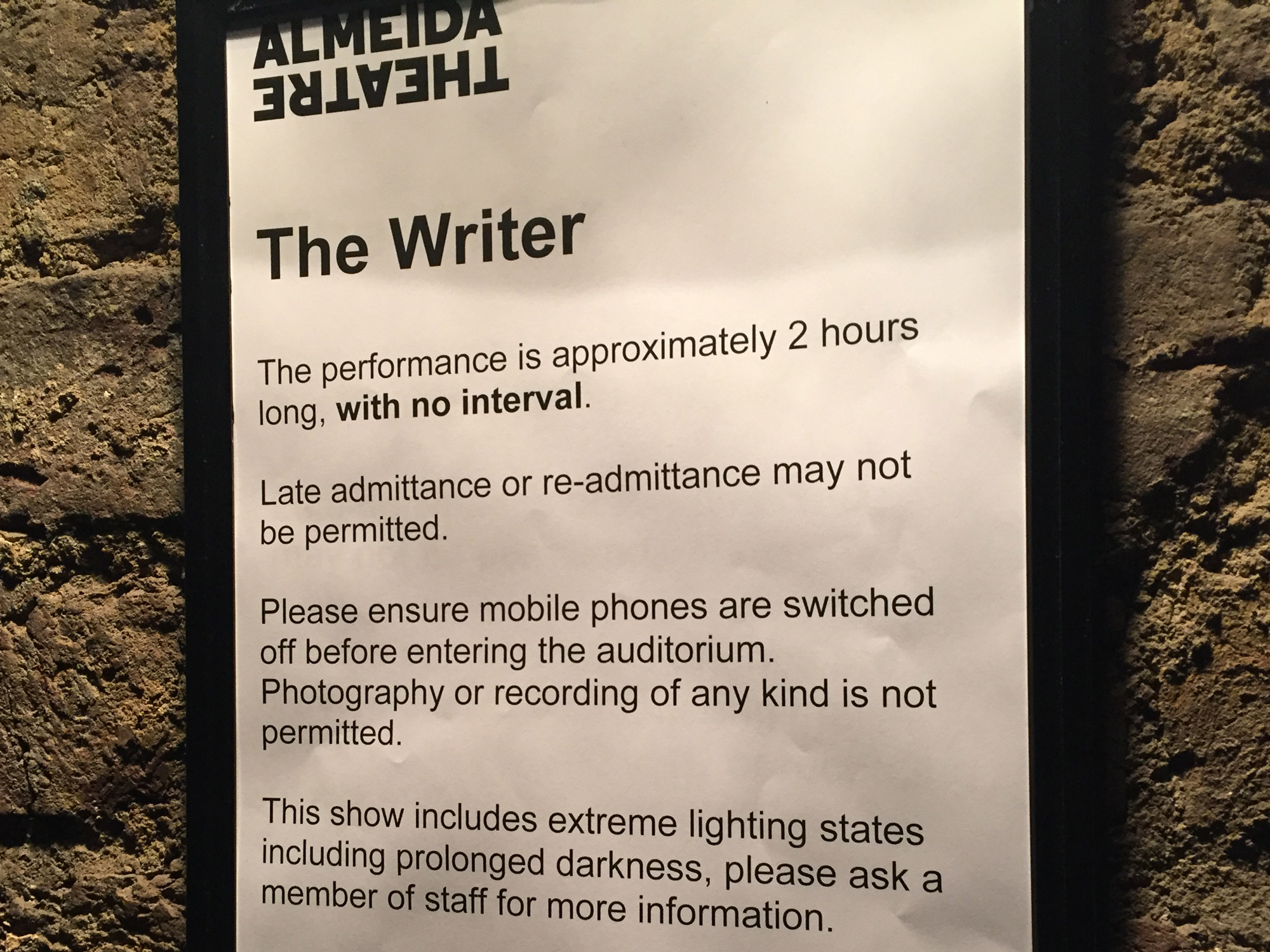 A sign, mounted on a brick wall. The sign read 'The Writer' and has a notifications about the event.