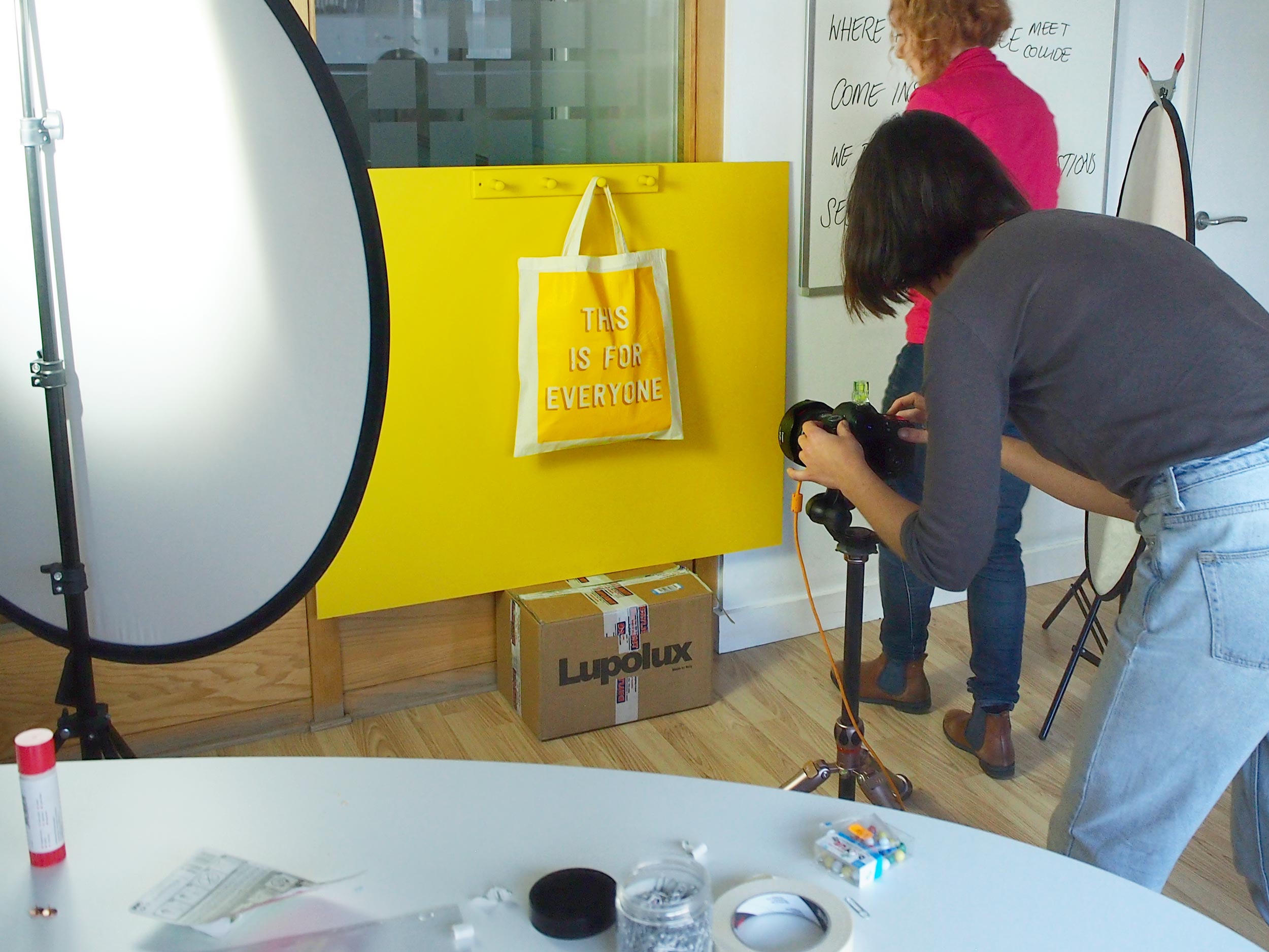 A studio set up with a photographer, shooting an image of a yellow bag on a yellow backing board