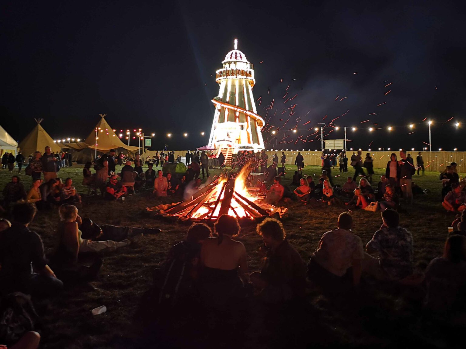 Campers round the fire, in front of a new addition to this year's festival – a helter-skelter