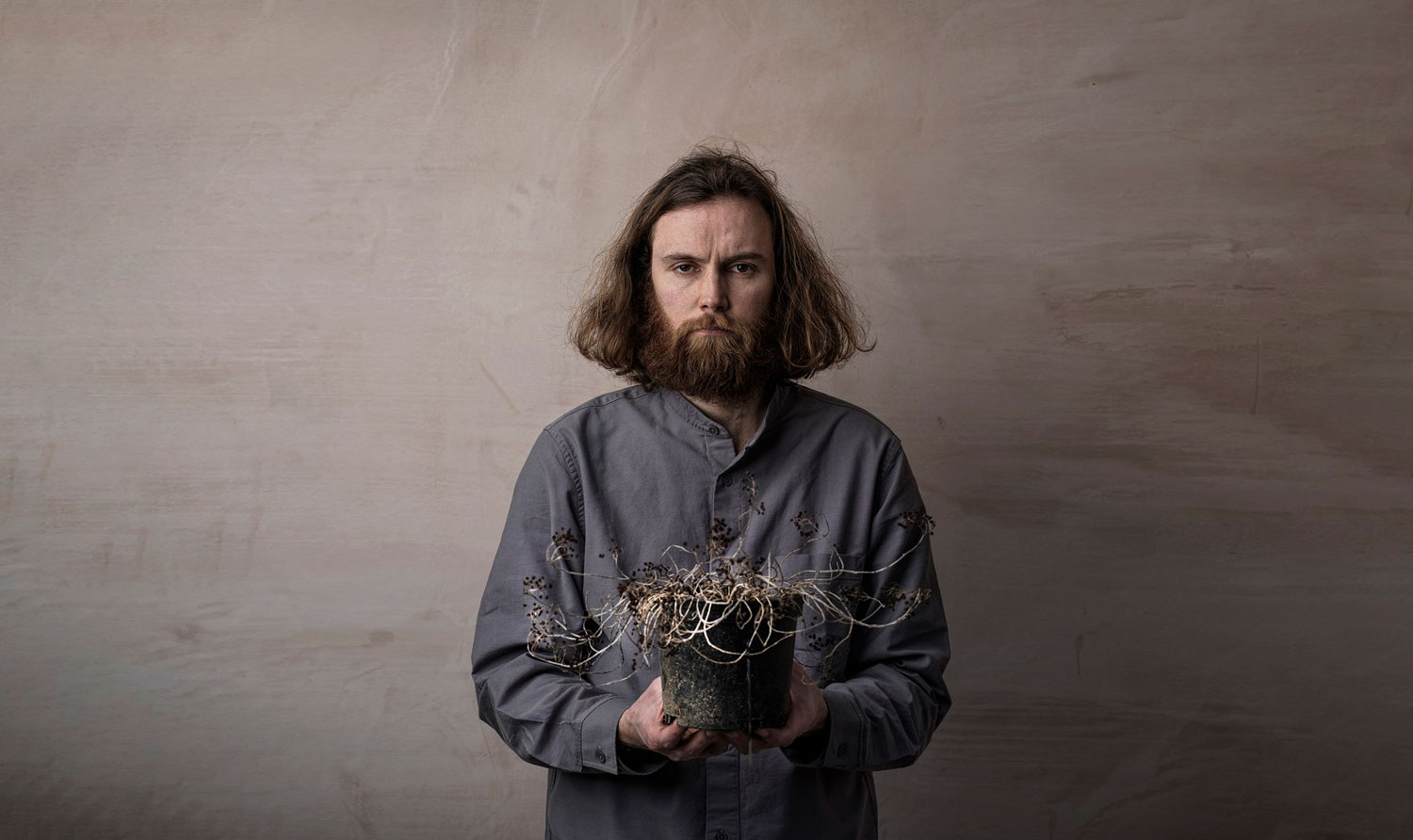 An image of the comedian Rob Auton looking gloomy holding a dead plant depicting the passage of time