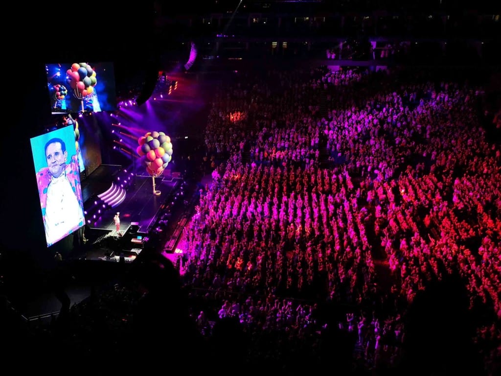 Looking down on a crowd of thousands, all looking at a single figure on stage. 