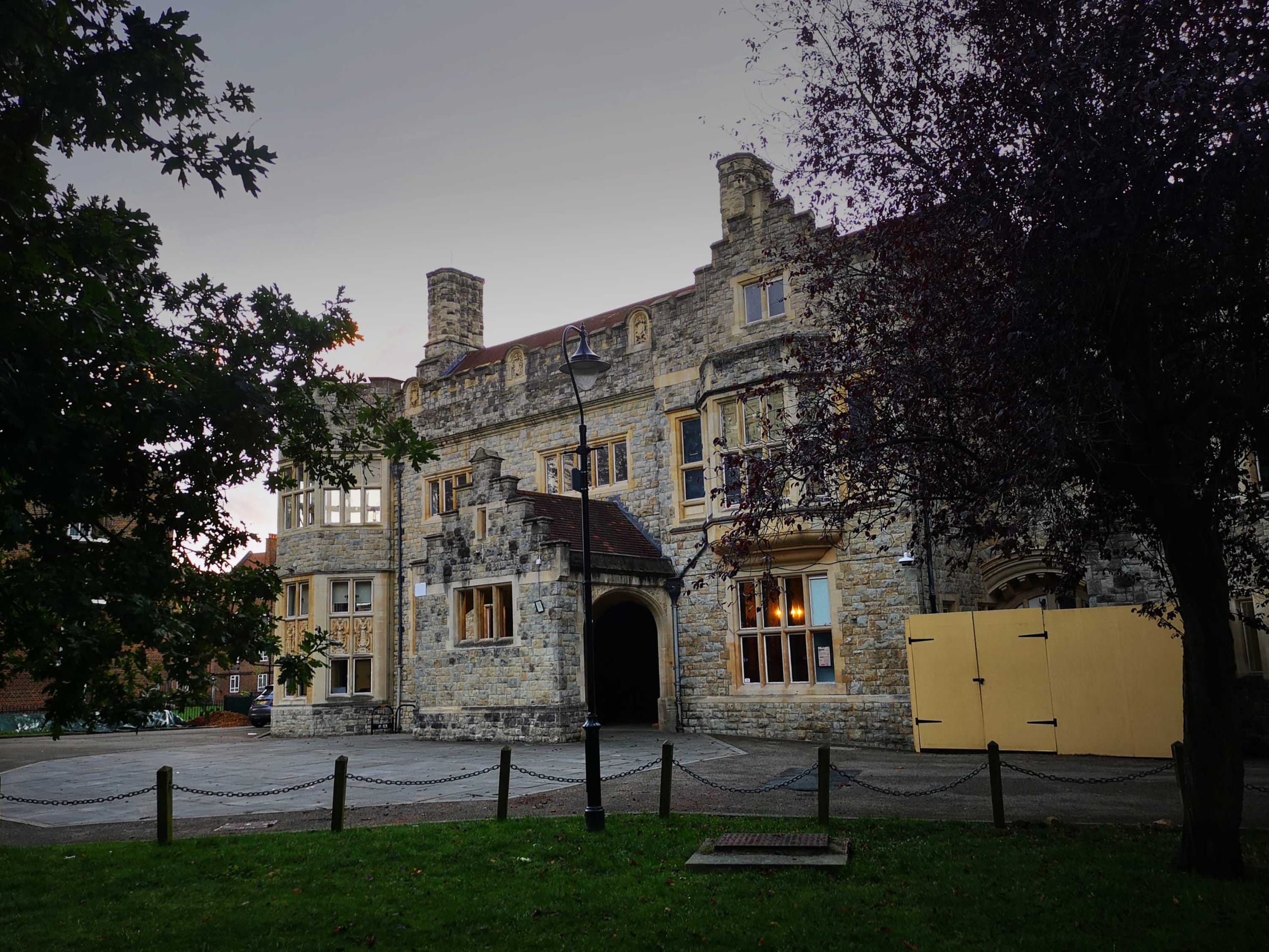 At dusk, through trees we see a faux medieval 'mansion'.