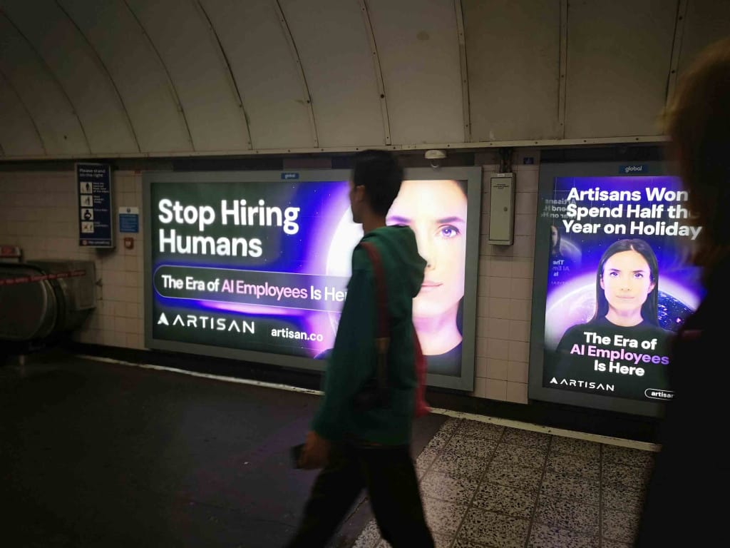 Posters in a tube station, mounted on the walls. They read 'Stop hiring Humans'. 